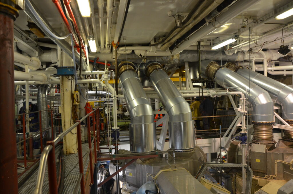 Maschinenraum mit mehreren silbernen Abgaskanalbögen über Generatoren